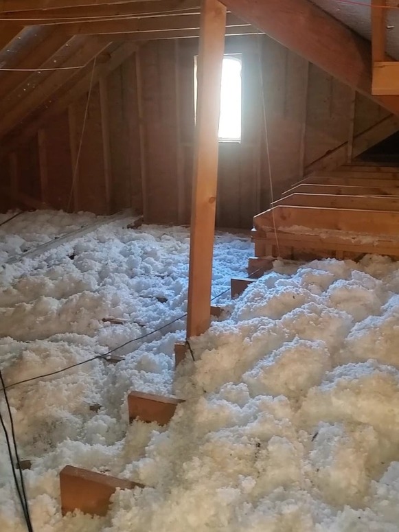 Finished attic with blown-in fiberglass insulation covering the ceiling joists