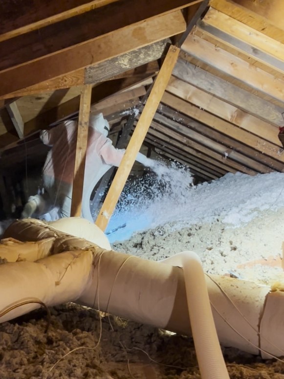 Blown-in fiberglass insulation being installed in a residential attic